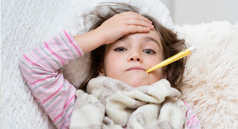 Young child with a thermometer in her mouth and a hand to her forehead looking upset